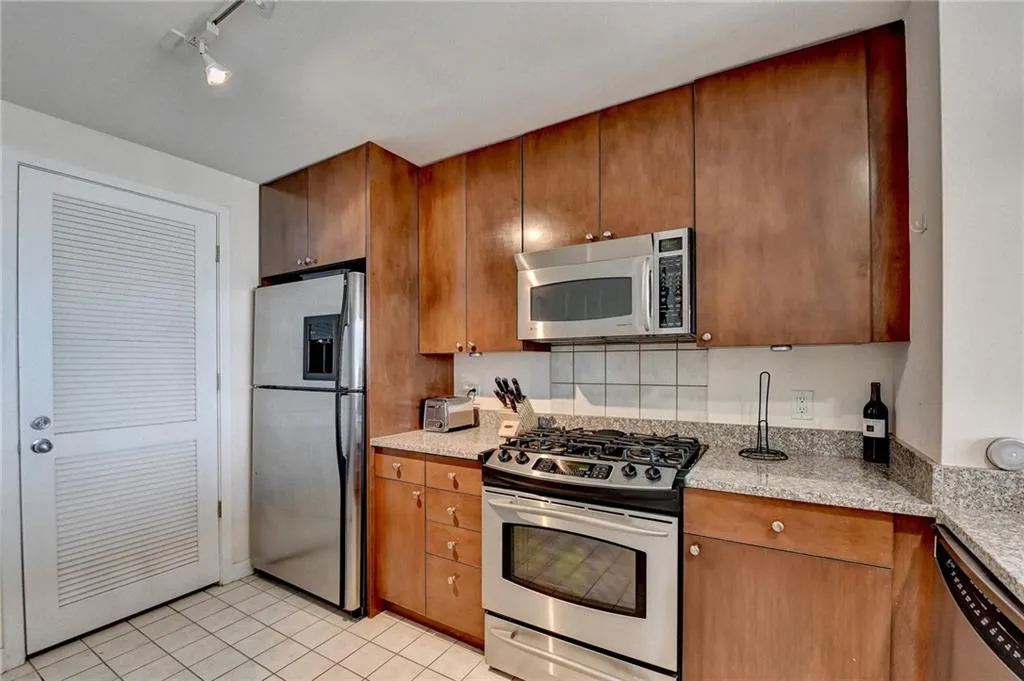 Kitchen with light stone countertops, appliances with stainless steel finishes, and light tile patterned floors