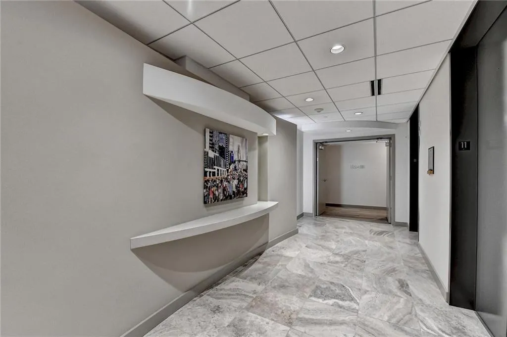 Hallway with elevator and a drop ceiling
