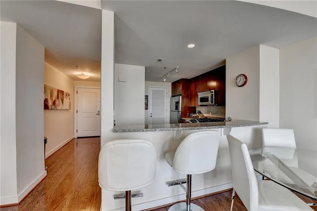 Kitchen featuring stainless steel appliances, light stone counters, kitchen peninsula, a breakfast bar, and light wood-type flooring