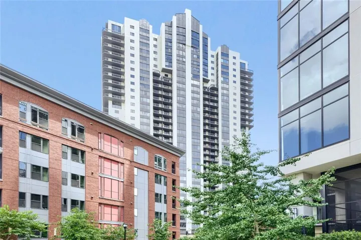 Contemporary high-rise building featuring a sleek glass facade and multiple private balconies