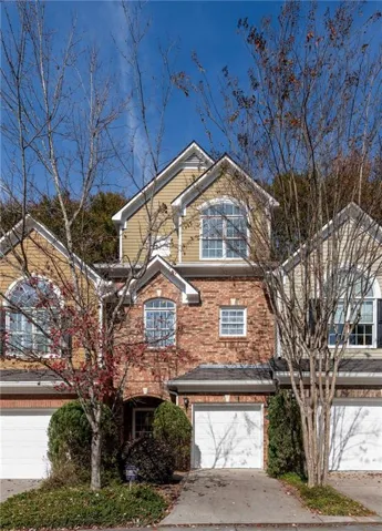 Traditional-style home featuring driveway, an attached garage, and brick siding