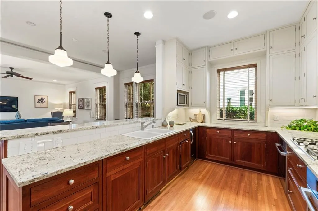 Kitchen featuring hanging light fixtures, a peninsula, tasteful backsplash, light wood-style floors, and recessed lighting