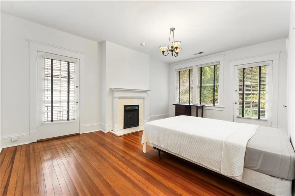 Bedroom with hardwood / wood-style flooring, access to exterior, a brick fireplace, and a chandelier