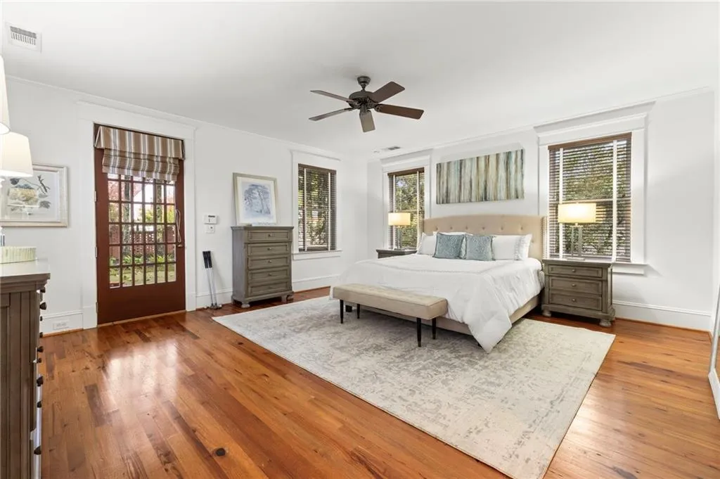 Bedroom featuring multiple windows, crown molding, wood-type flooring, and a ceiling fan