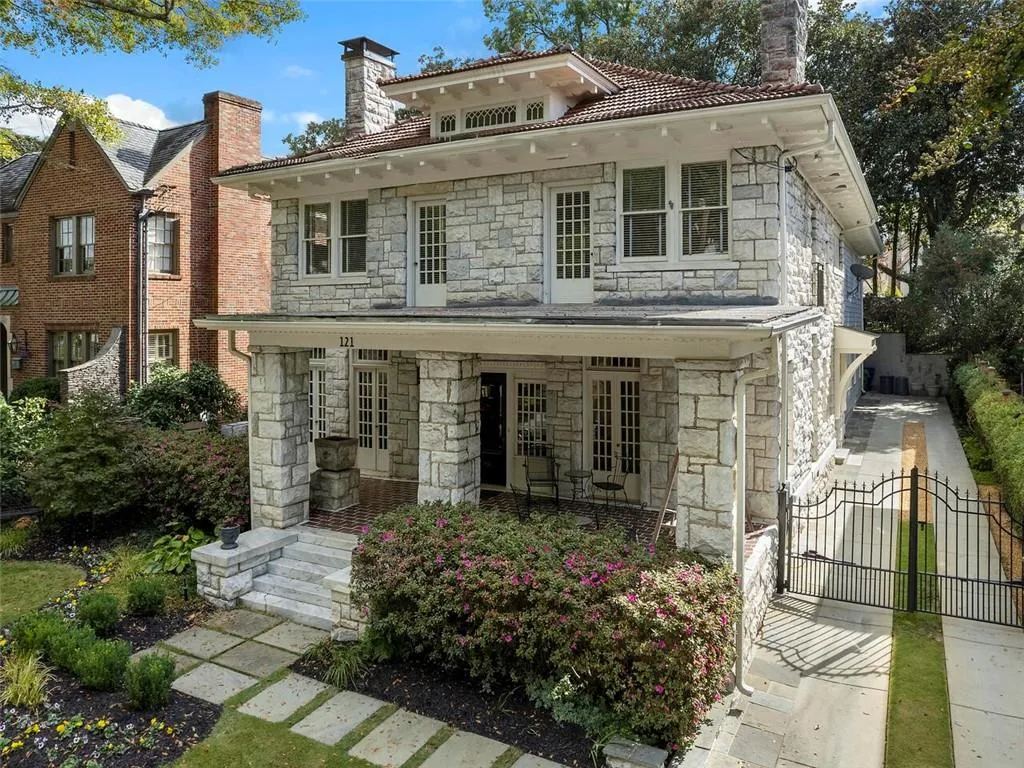 View of front of property featuring stone siding, a gate, a chimney, and fence
