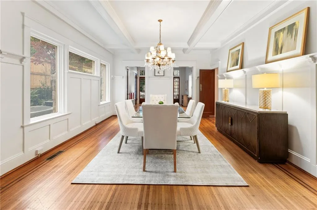 Dining area with a decorative wall, beam ceiling, a chandelier, and light wood-style floors