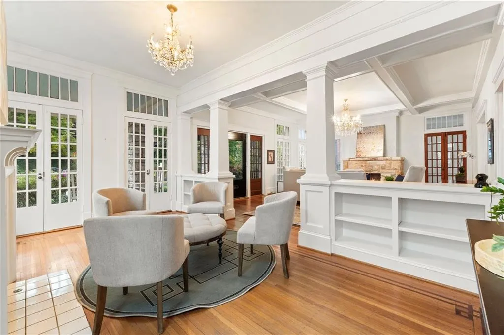 Living area with a chandelier, french doors, ornate columns, plenty of natural light, and beamed ceiling