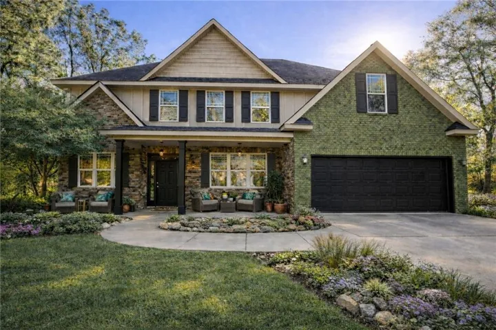 Craftsman-style home with covered porch, driveway, a front yard, outdoor furniture, and a garage
