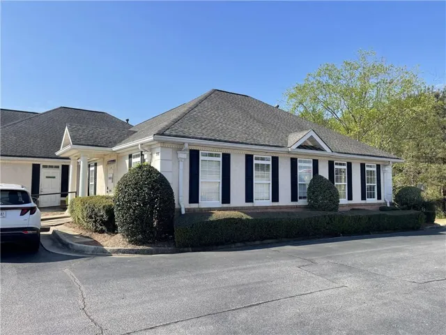 View of front of house featuring roof with shingles and stucco siding