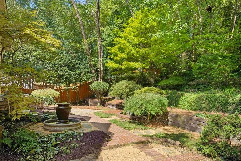 Landscaped yard featuring a tiered water feature, brick pathways, and mature greenery