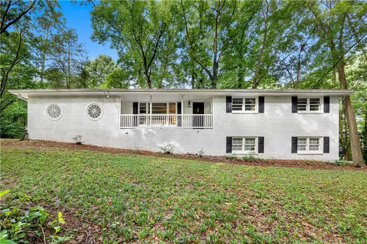 White-painted brick exterior featuring a covered front porch with white railings, black shutters, and decorative circular windows