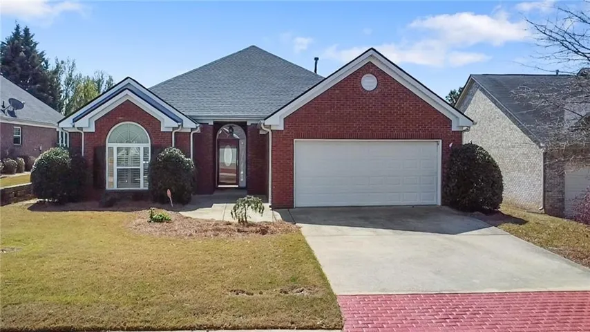 Brick-front residence featuring a two-car garage, arched entry, and a gabled roofline