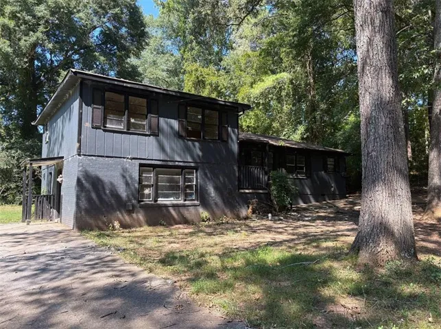 Two-story property featuring a dark-toned exterior, multiple windows with dark shutters, and a covered entry