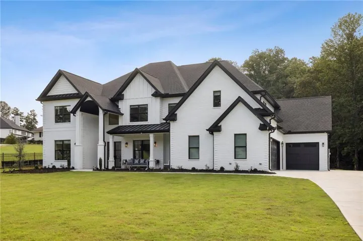 White brick exterior with dark trim, multiple gables, and a prominent covered front porch