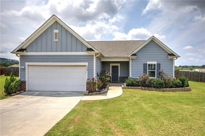 Single-story residence featuring blue siding, a white garage door, and a covered entry