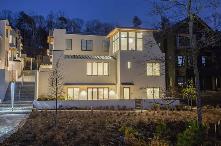 Modern stucco exterior with expansive windows, multi-level architectural design, and integrated outdoor lighting