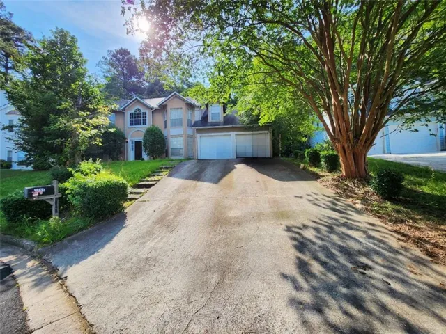 Two-story residence featuring a two-car garage, arched entryways, and a concrete driveway