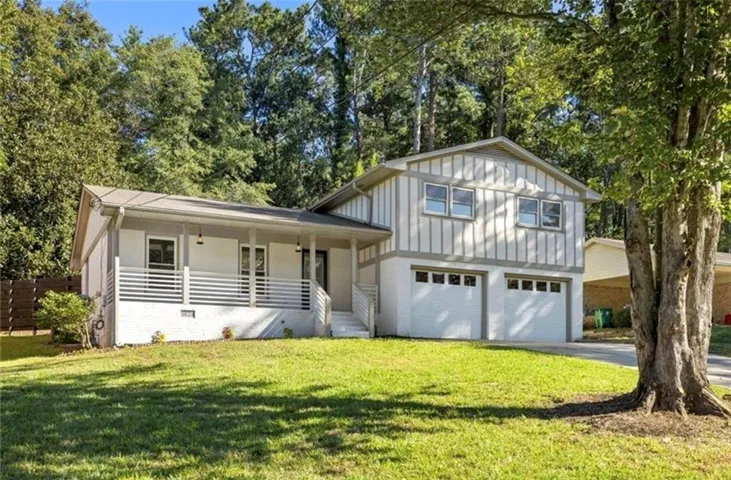 White exterior with grey trim featuring a covered porch, horizontal railing, and integrated two-car garage