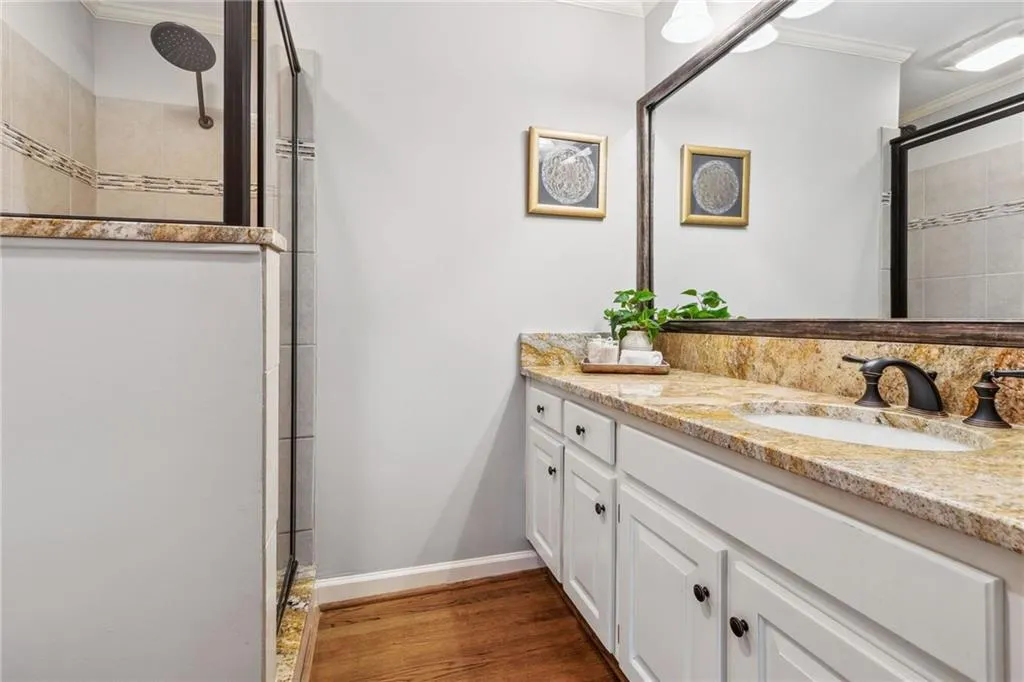 Bathroom featuring vanity with granite counters and tiled shower.