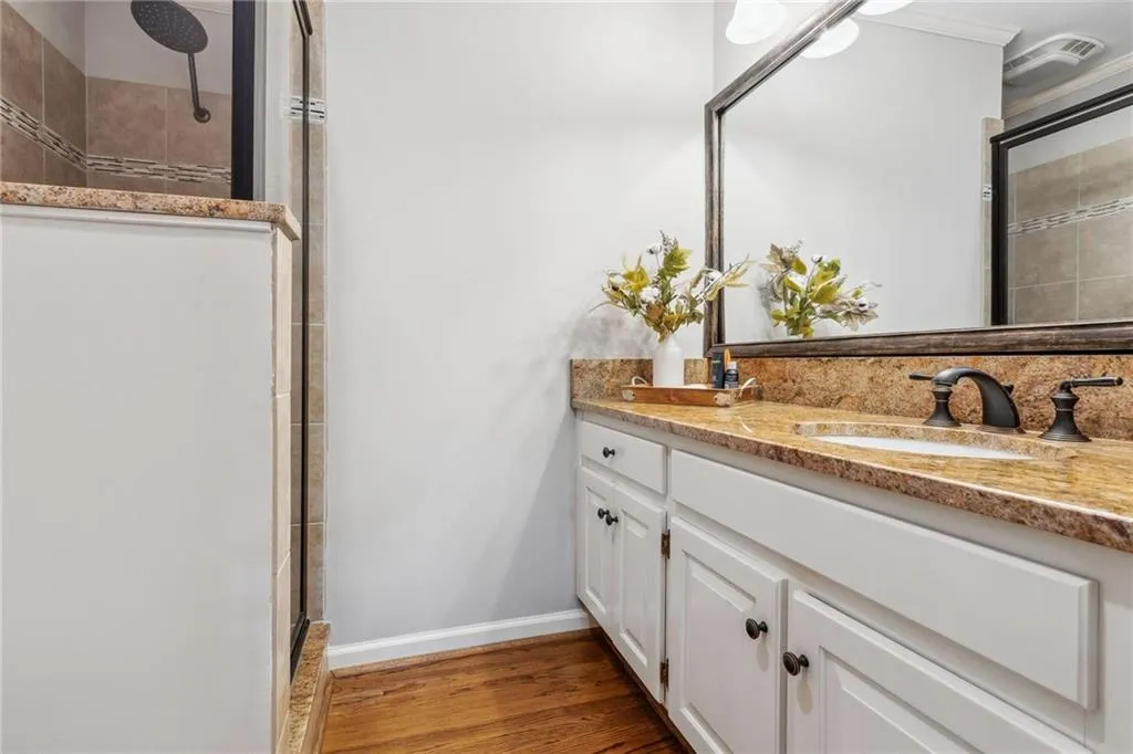 Bathroom with tiled shower and granite vanity.