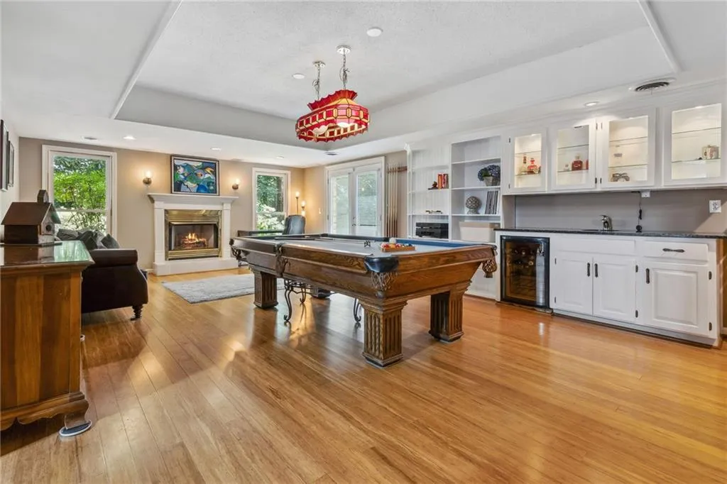 Terrace level recreation room with a wealth of natural light, wine cooler, wet bar, pool table, fireplace.