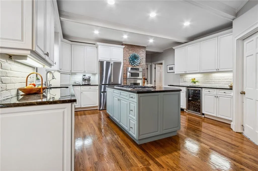 Kitchen with beverage cooler, white cabinets, a kitchen island, and dark hardwood / wood-style flooring