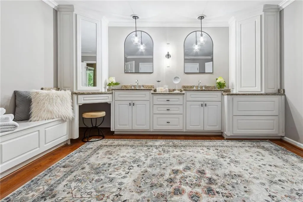 Dual sinks and vanity with generous custom cabinets and storage bench