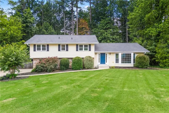Beautifully maintained residence featuring light-colored siding, a dark shingle roof, and a vibrant blue front door