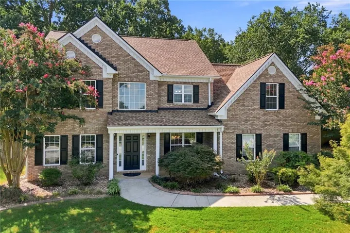 Brick exterior with white trim, covered front porch, gabled rooflines, and mature landscaping