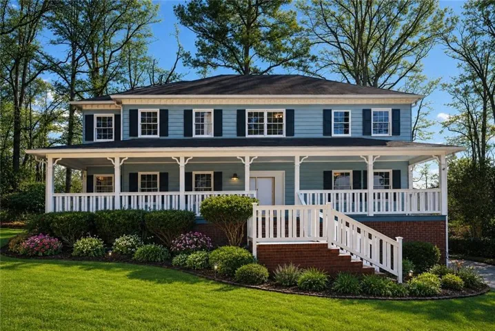 Two-story residence featuring blue siding, white trim, and a full-width covered front porch with white railings