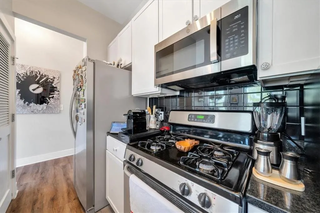 Kitchen featuring white cabinets, appliances with stainless steel finishes, and wood-type flooring