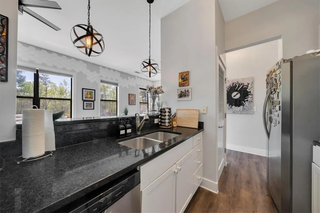 Kitchen featuring sink, appliances with stainless steel finishes, white cabinets, a wealth of natural light, and decorative light fixtures