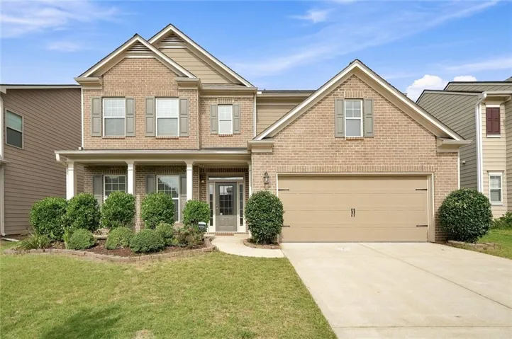 Two-story brick and siding exterior with a covered front porch, attached garage, and landscaping