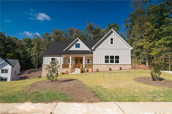 Contemporary farmhouse exterior with board and batten siding, brick foundation, a covered front porch, and a dark shingle roof