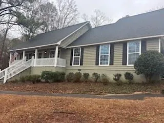 Ranch-style exterior with light green siding and dark shutters