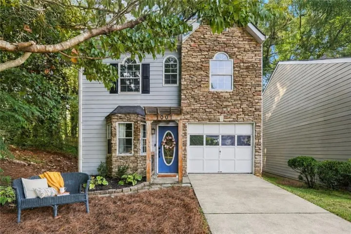 Stone and siding facade featuring an arched window, bay window with stone accent, and a single-car garage