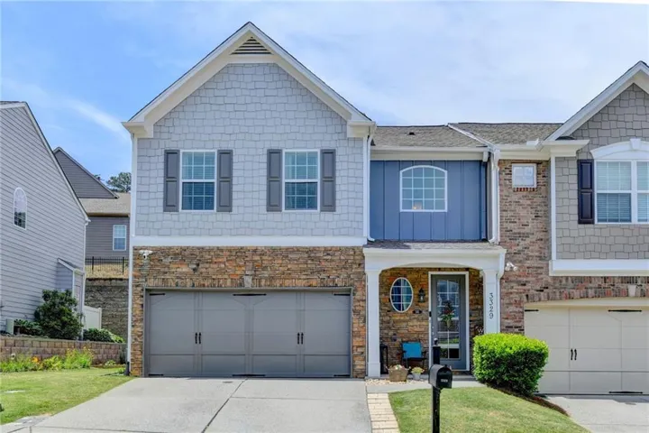 Two-story exterior with stone and siding accents, featuring a two-car garage and a paved driveway