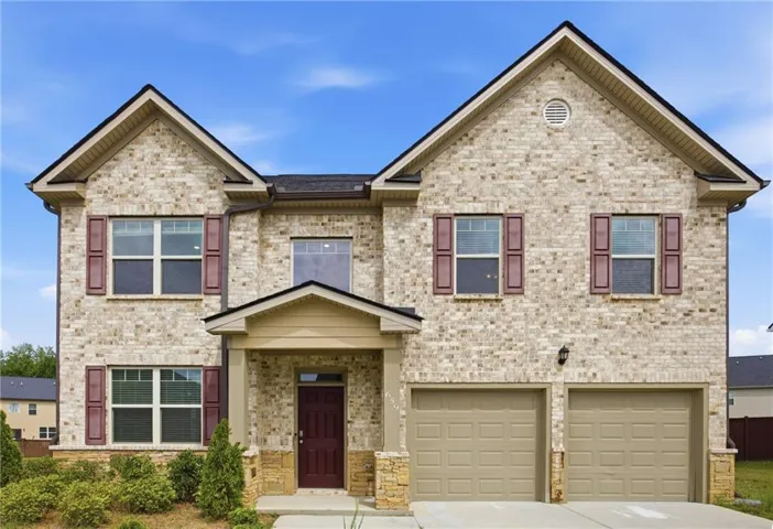 Brick exterior with stone accents, covered front entry, two-car garage, and shuttered windows