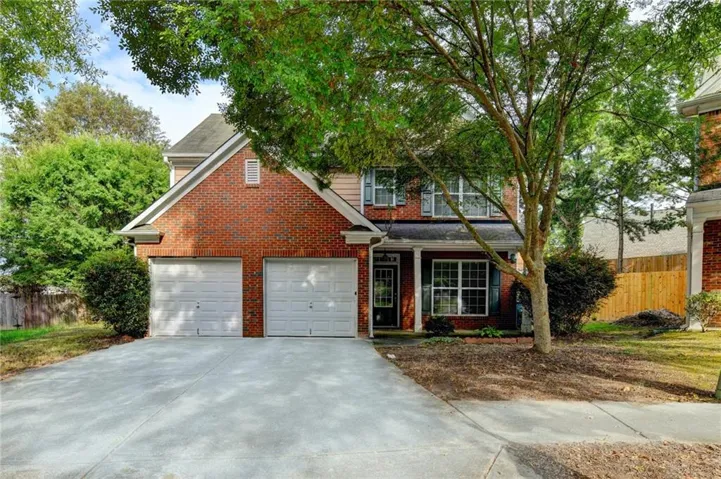 Brick and siding exterior with a covered entry, two-car garage, concrete driveway, and mature landscaping