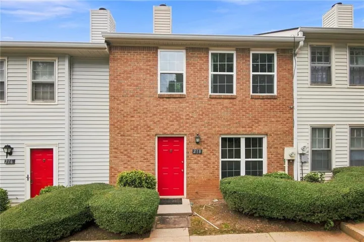 Brick and siding exterior featuring a bright red entry door with a transom window
