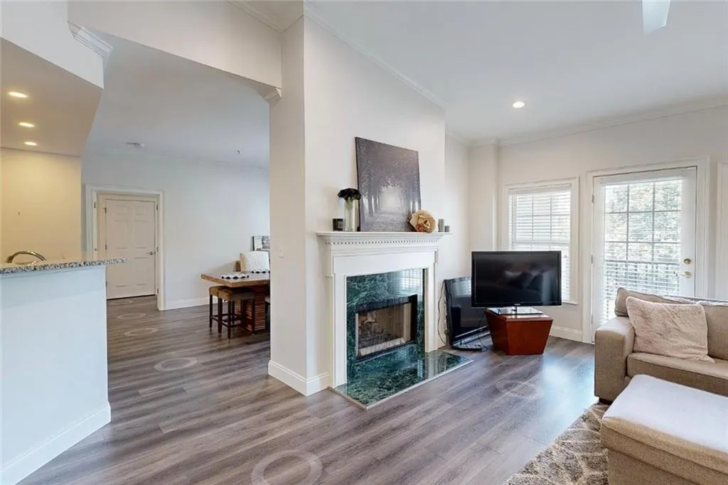 Living area with ornamental molding, a fireplace, wood finished floors, and recessed lighting