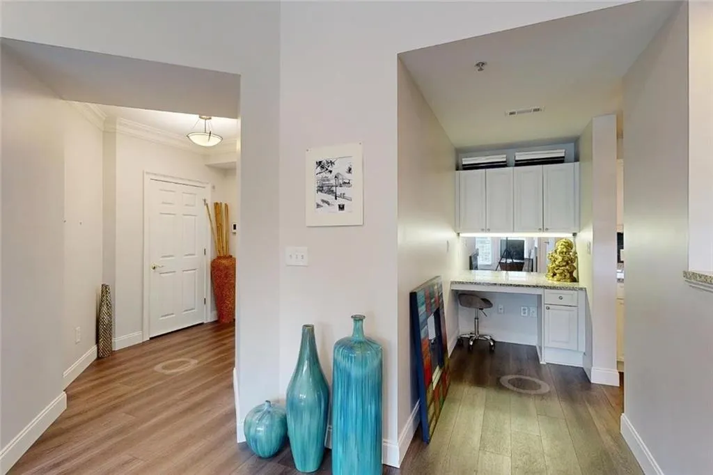 Corridor featuring dark wood-style floors, a desk, and crown molding