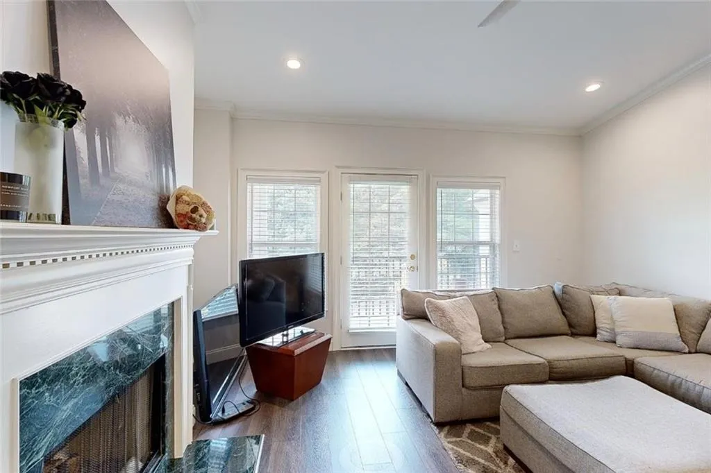 Living room with a high end fireplace, healthy amount of natural light, wood finished floors, ornamental molding, and recessed lighting