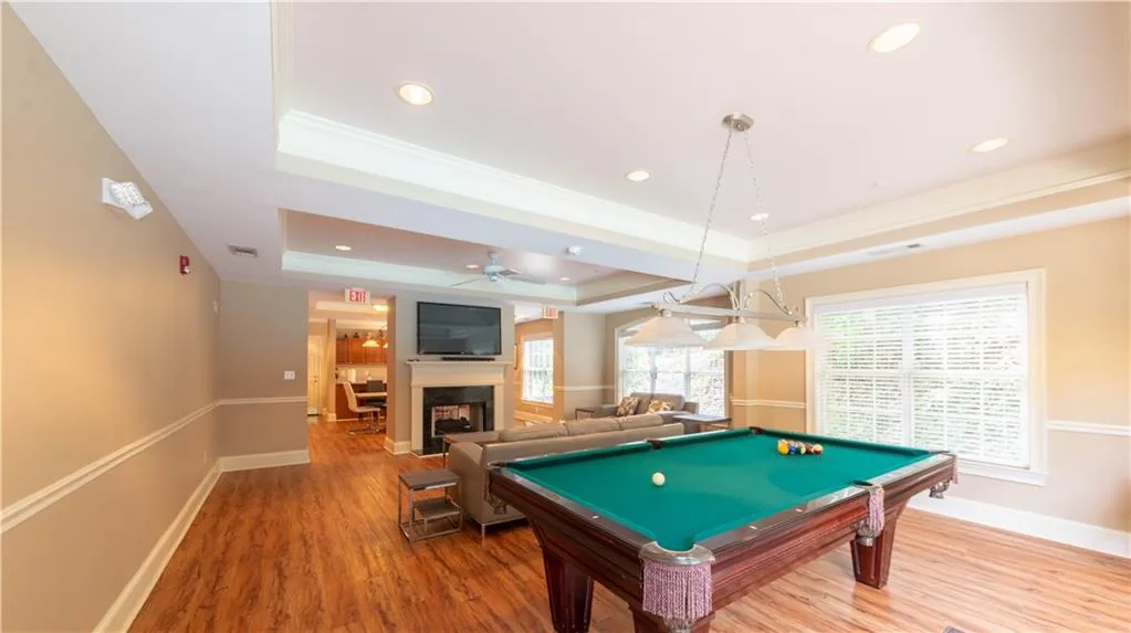 Playroom featuring a raised ceiling, crown molding, wood finished floors, ceiling fan, and billiards table