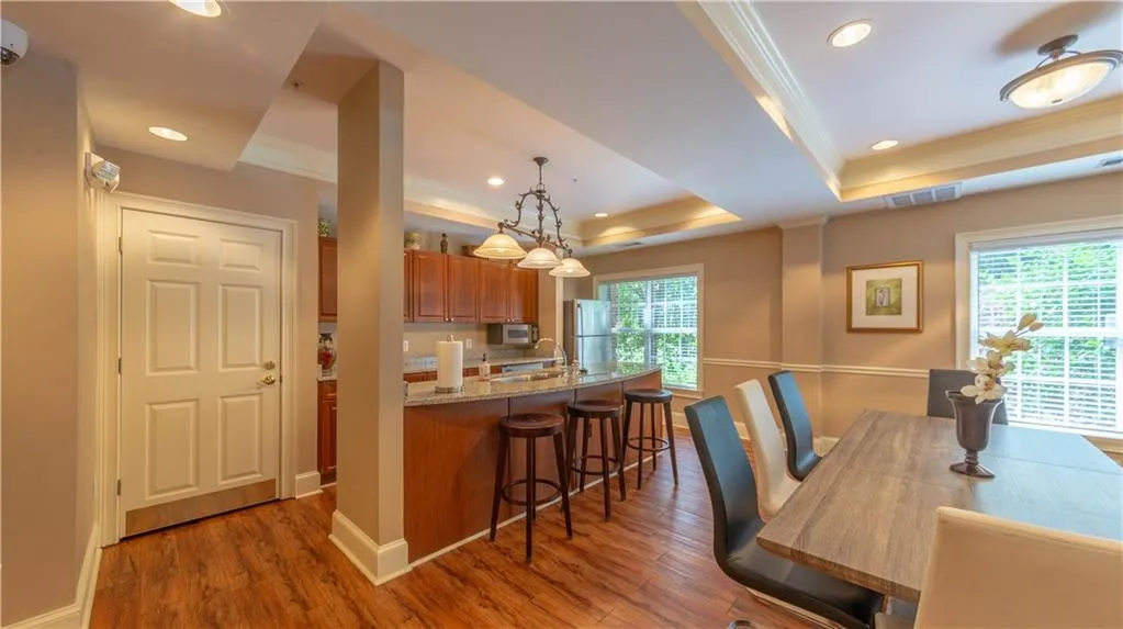 Kitchen with a tray ceiling, crown molding, brown cabinets, a kitchen bar, and plenty of natural light