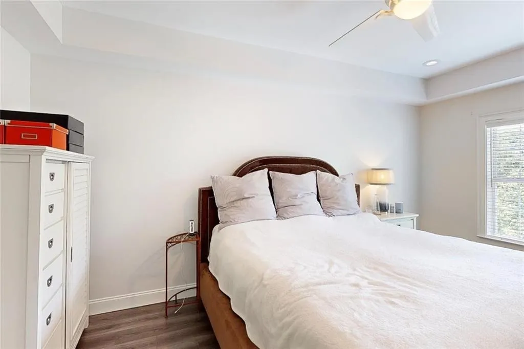 Bedroom featuring wood finished floors, a ceiling fan, a tray ceiling, and recessed lighting