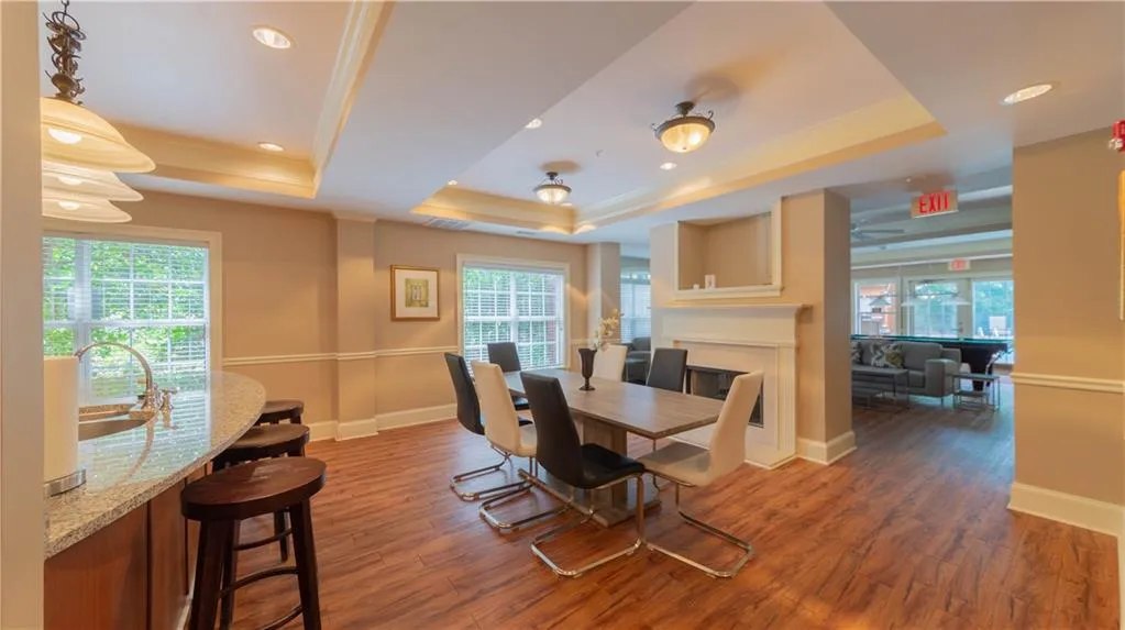 Dining room featuring a tray ceiling, plenty of natural light, wood finished floors, ornamental molding, and recessed lighting