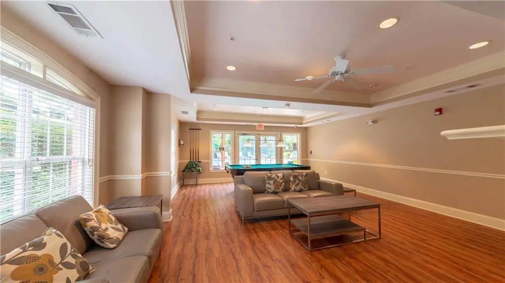 Living area featuring billiards, a tray ceiling, crown molding, wood finished floors, and a ceiling fan