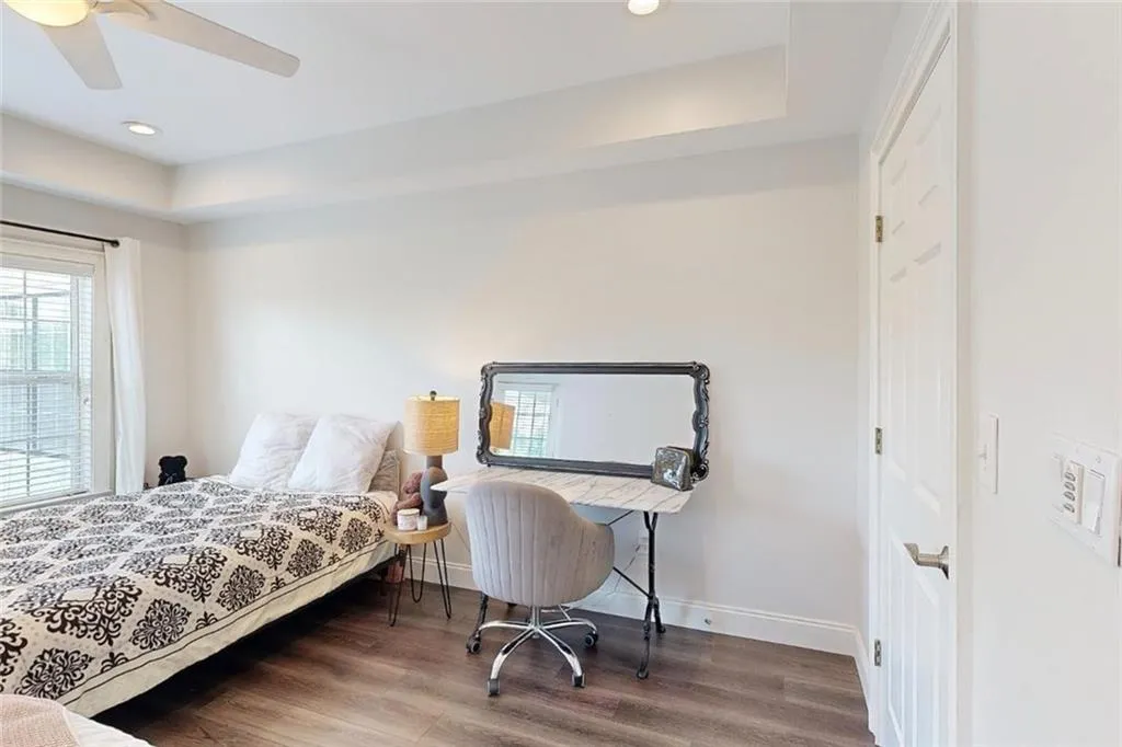 Bedroom with wood finished floors, recessed lighting, ceiling fan, and a tray ceiling