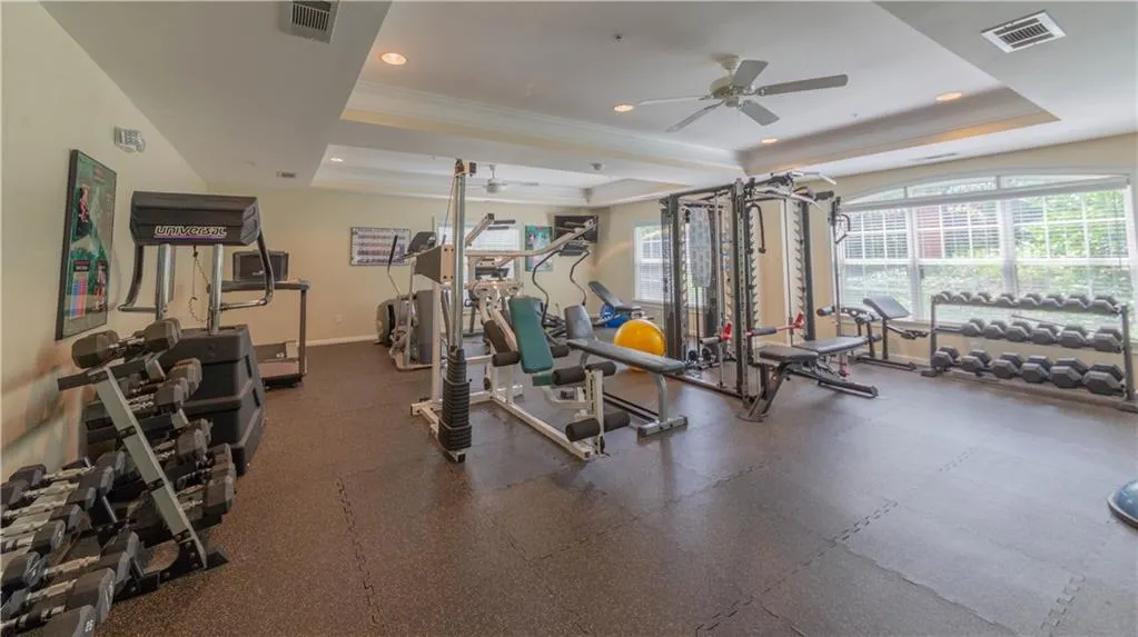 Workout area with a raised ceiling, plenty of natural light, ceiling fan, crown molding, and recessed lighting